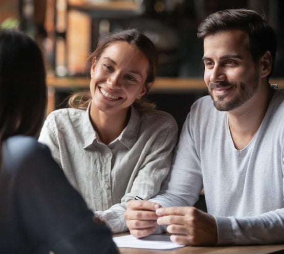 Biracial woman caucasian man listen vacancy candidate sitting together at table at job interview. Diverse couple communicating with real estate agent, successful meeting ready to sign contract concept